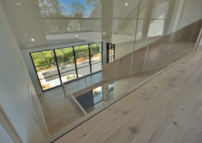 Interior-floor-to-ceiling-frameless-glass-wall-overlooking-the-main-entry-staircase